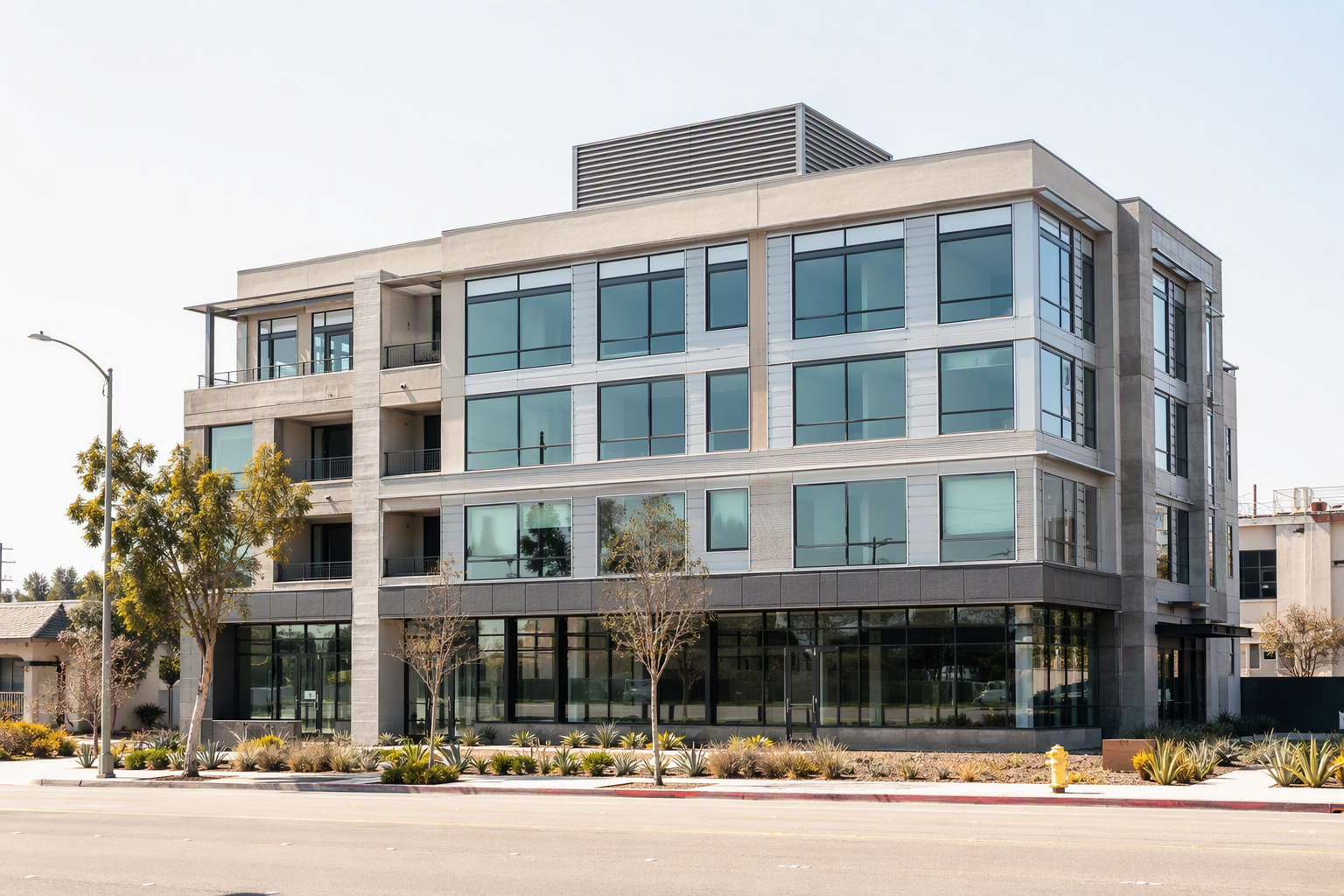 Mid-rise commercial building in Signal Hill CA on a hot summer day, showing rooftop elevator machine room ventilation — extreme heat elevator performance concerns.