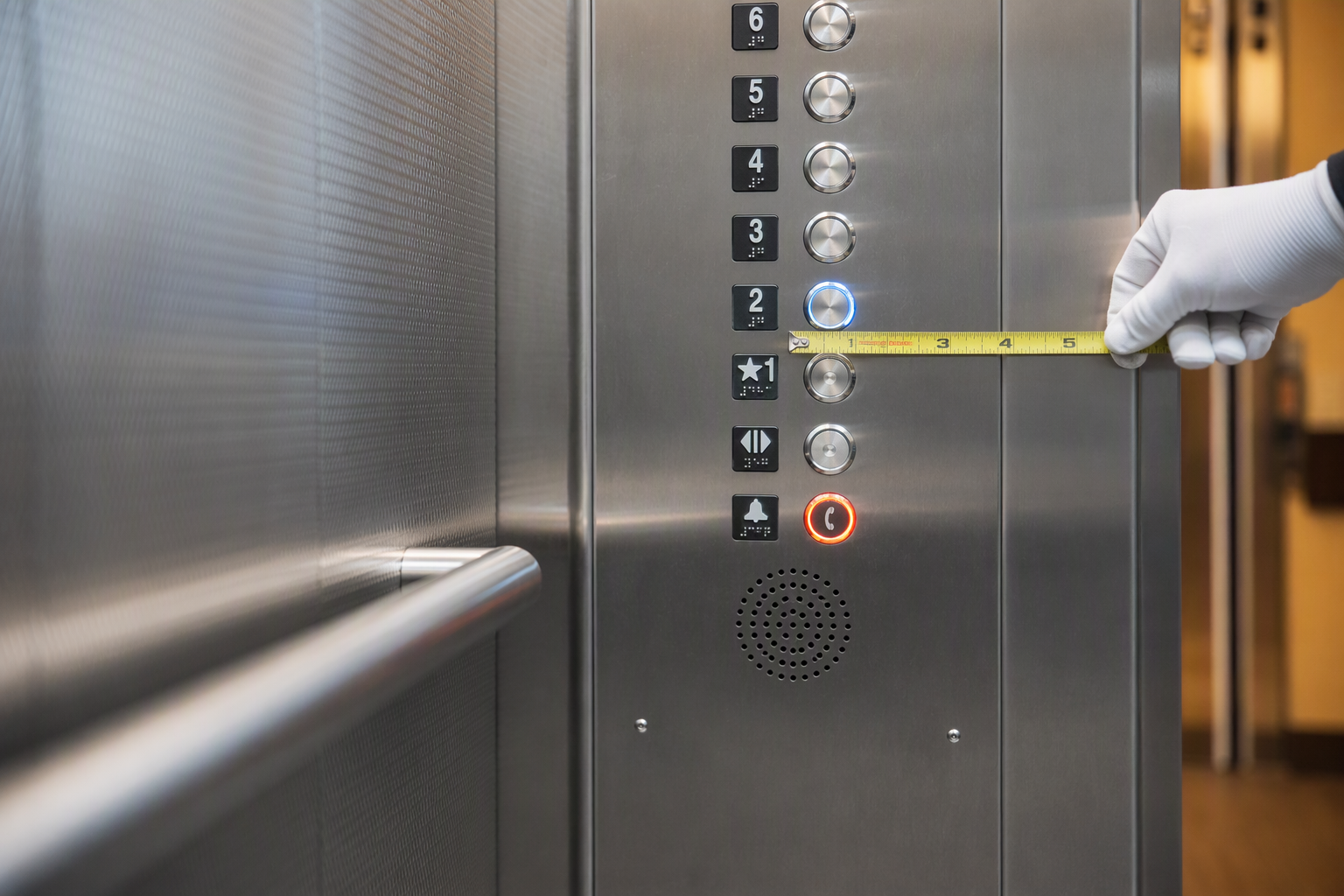 ADA Control Panel Height and Braille Signage Check Close-up of ADA elevator control panel with Braille signage and correct button height being measured during a California commercial building compliance inspection
